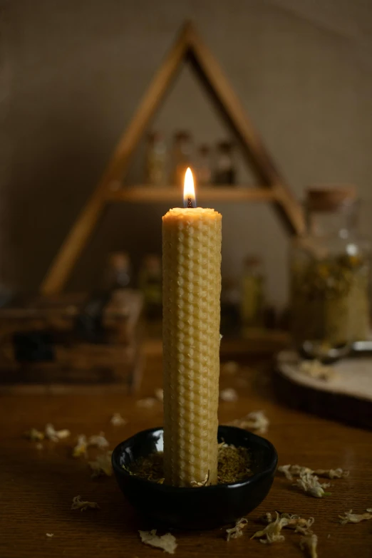 a lit candle sits in a black bowl filled with scrap paper