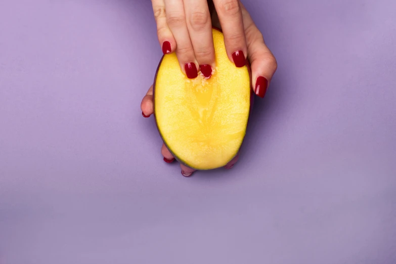 a hand holding a fruit next to it's skin on top of a purple background