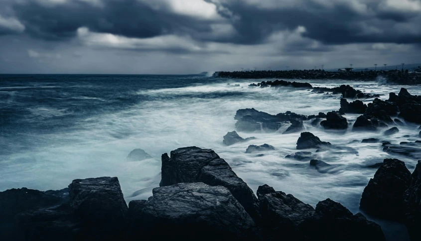 dark stormy skies and rocky shoreline in the ocean