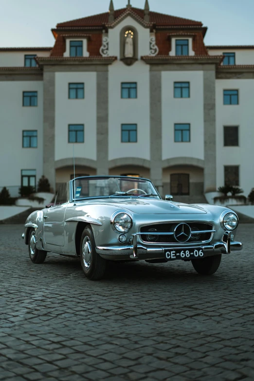 a silver mercedes sports car parked in front of a large building