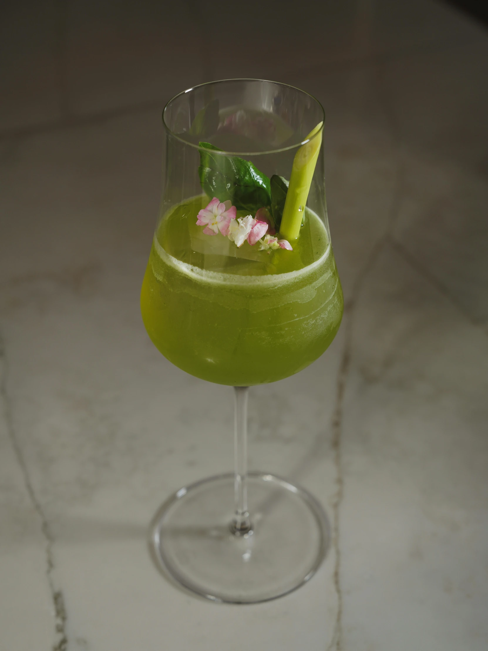 a green drink sits in a wine glass