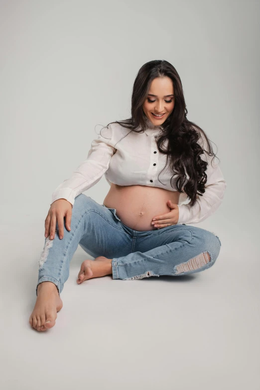 pregnant women is sitting with her legs crossed and looking at the camera