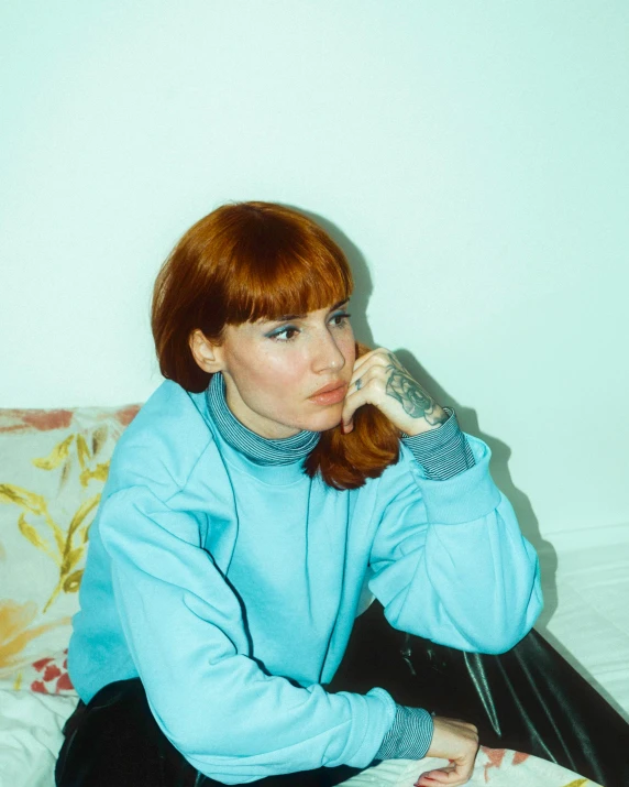 a red headed woman sits on the bed and talks on a cell phone