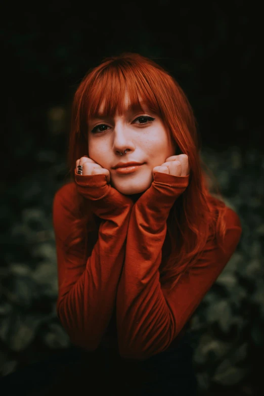 a beautiful red haired woman in an orange sweater posing