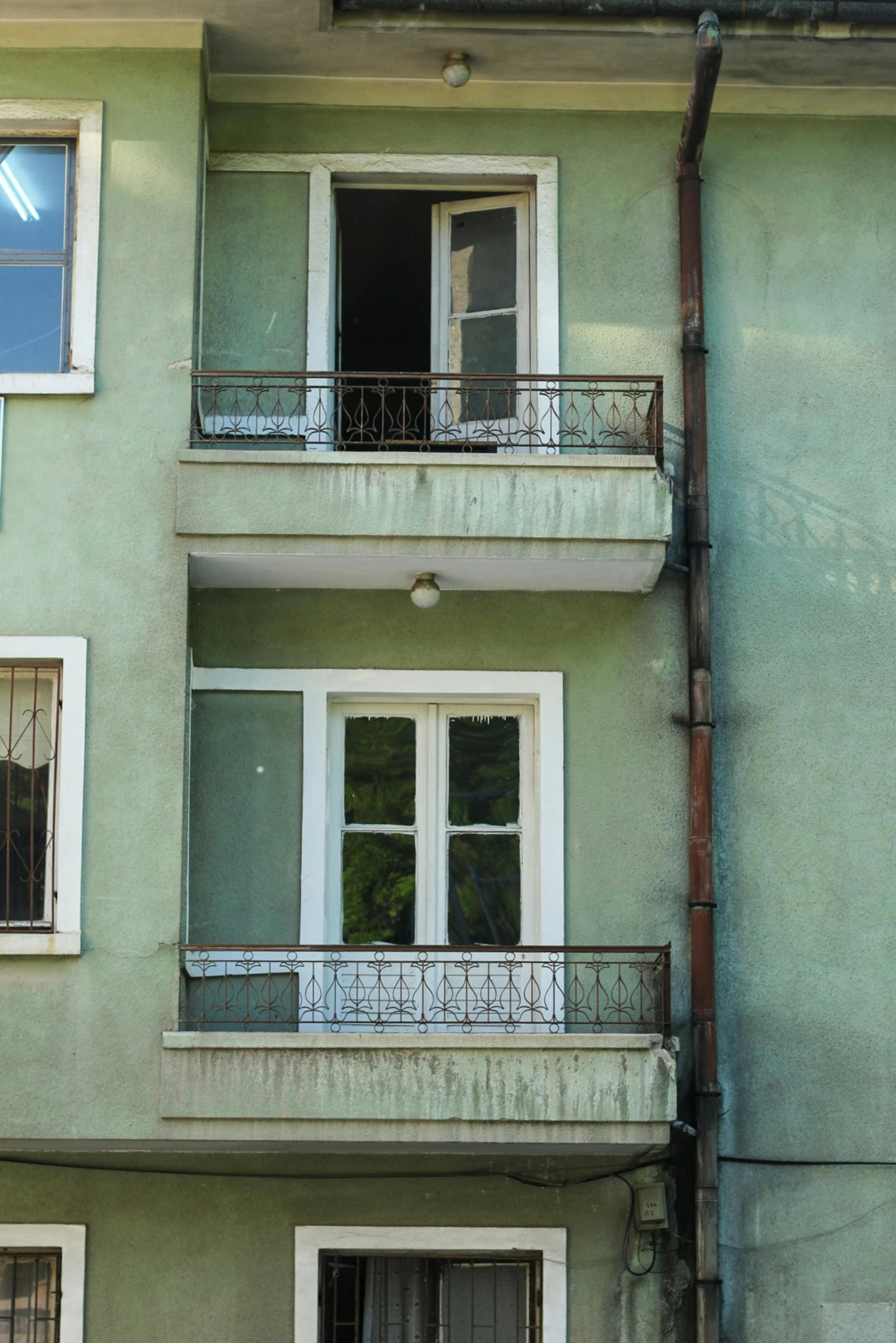 a green building with two windows and iron bars on the outside