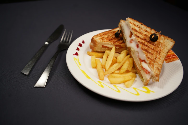 a sandwich with chips and cheese on a white plate with black fork