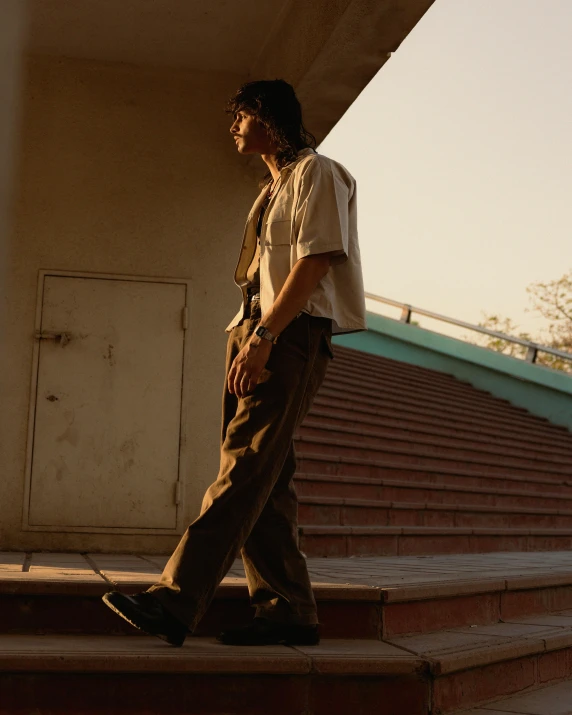 a man in a white shirt and tan pants walking up steps