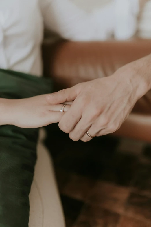 two people holding hands with a white ring on one