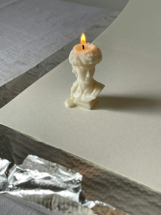 a candle sitting on a sheet of foil on a table