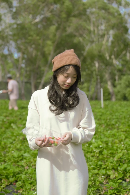 a little girl with a knitted hat standing in a field