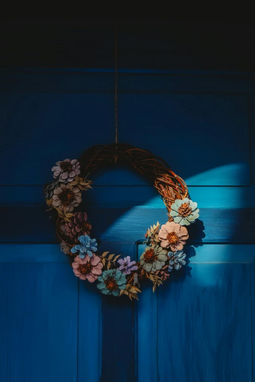 a blue door with a small wreath made out of flowers