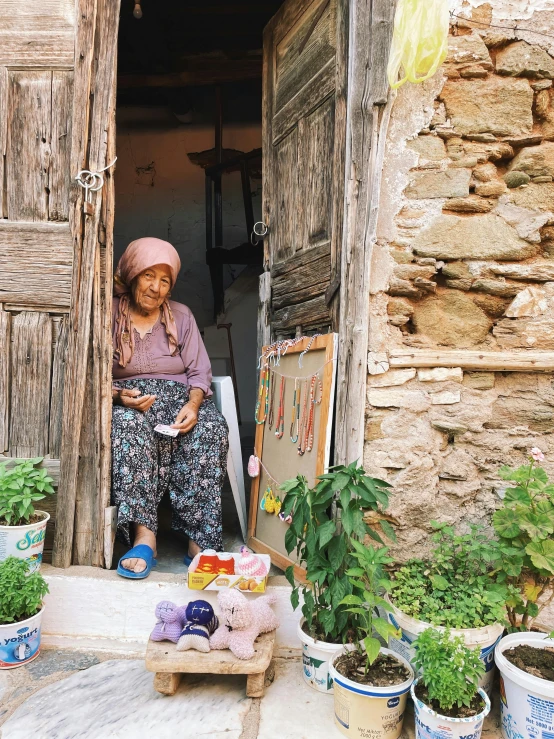 an asian woman sitting in the open door of a wooden building