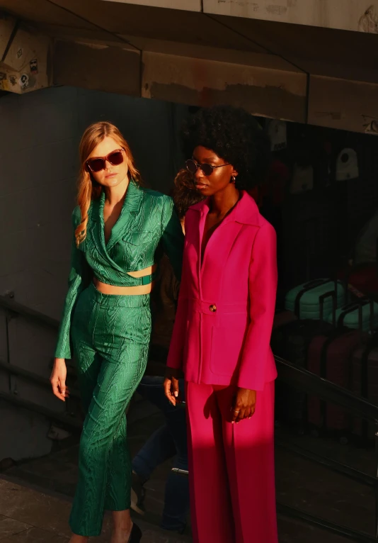 two women are dressed in green and pink at an event