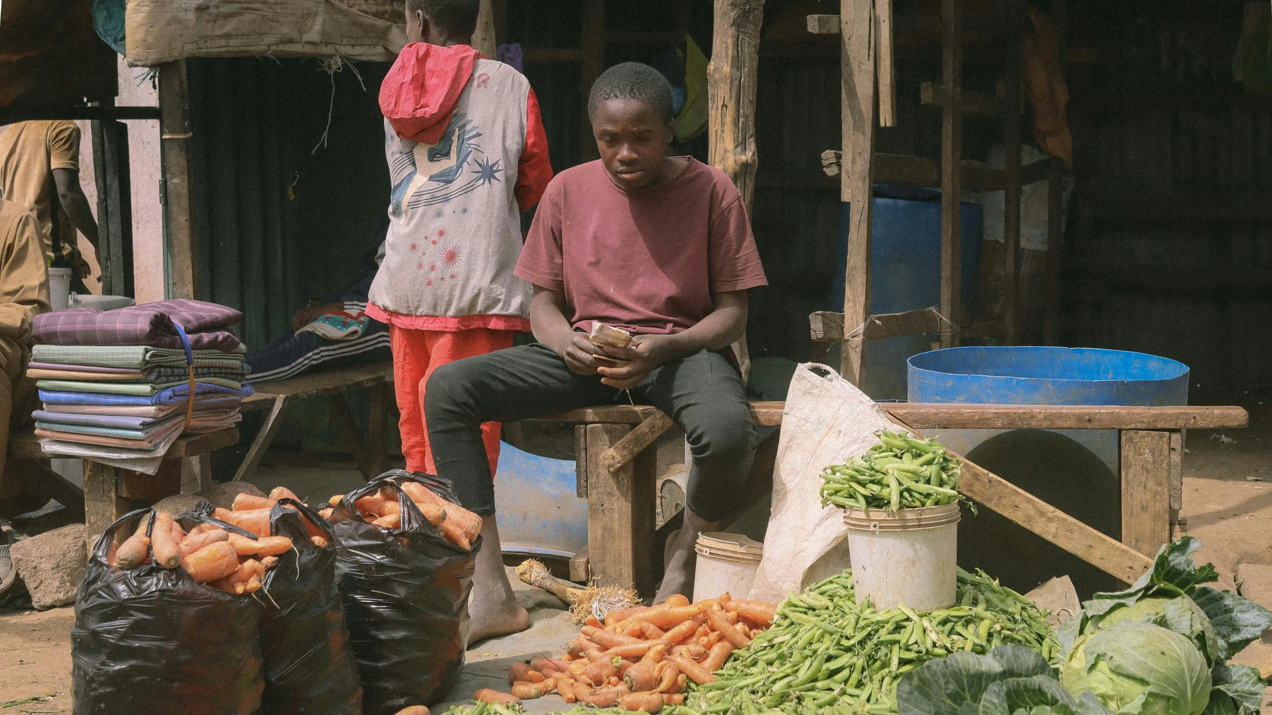 two men sit in front of an outdoor market