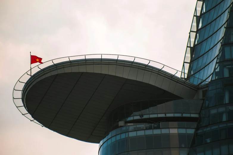 a red flag flying near a building under a cloudy sky