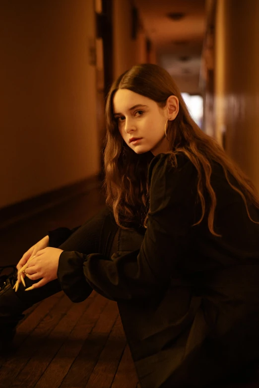 a woman is sitting in the hallway, looking sad