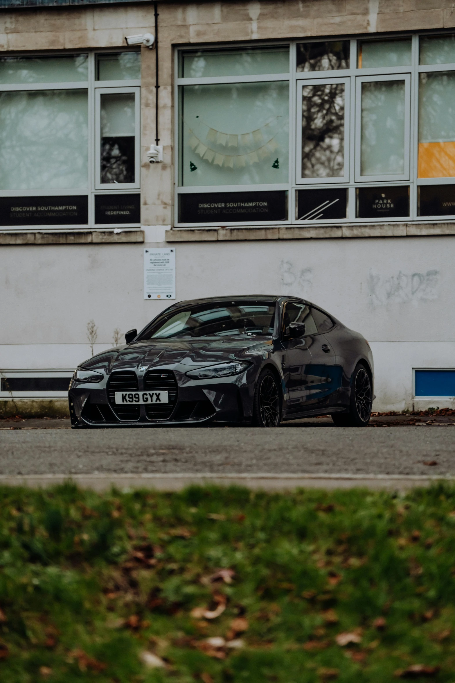 the black bmw is parked in front of the white building