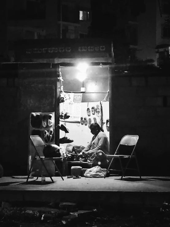 a man sits on a chair near a street sign at night