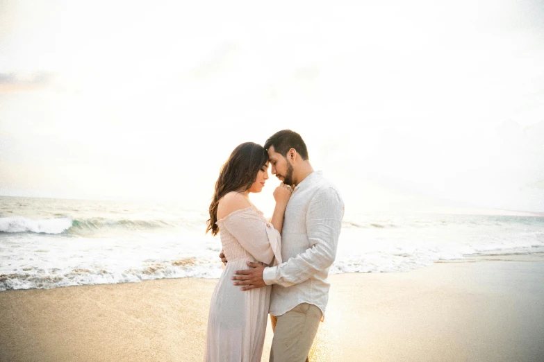 a couple cuddles on the beach as the sun goes down