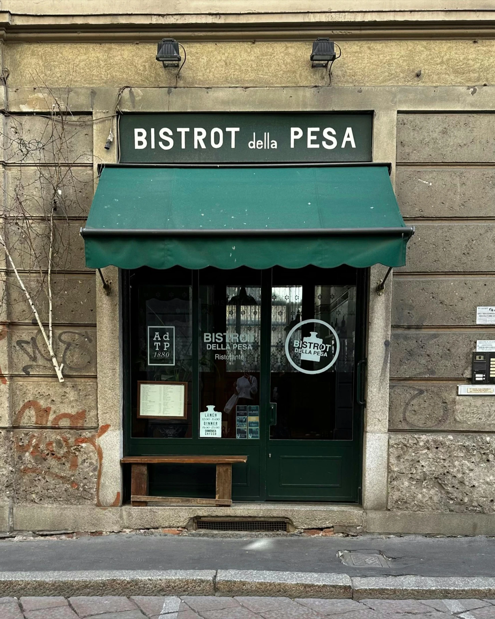 a small store with a bench and sidewalk below