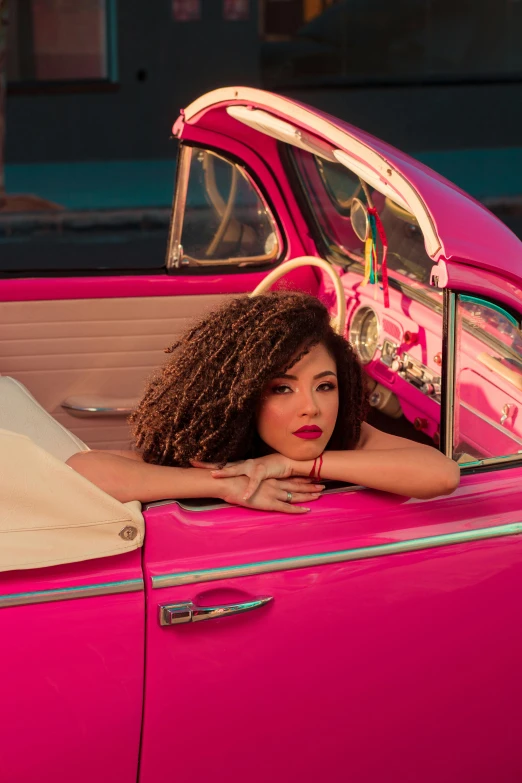 woman laying in pink car with her head out window