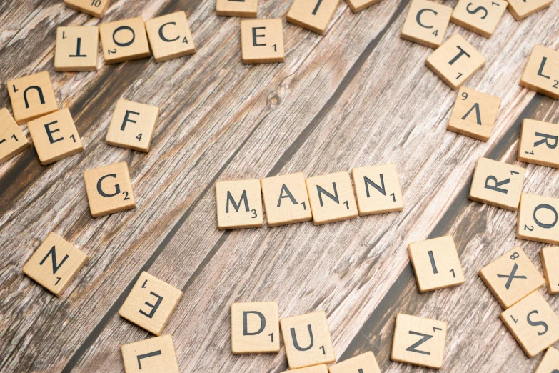 several different types of scrabble letters are laid out on a wood surface