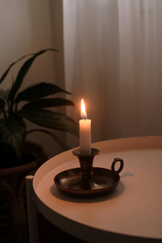 a lit candle on a small plate on the table