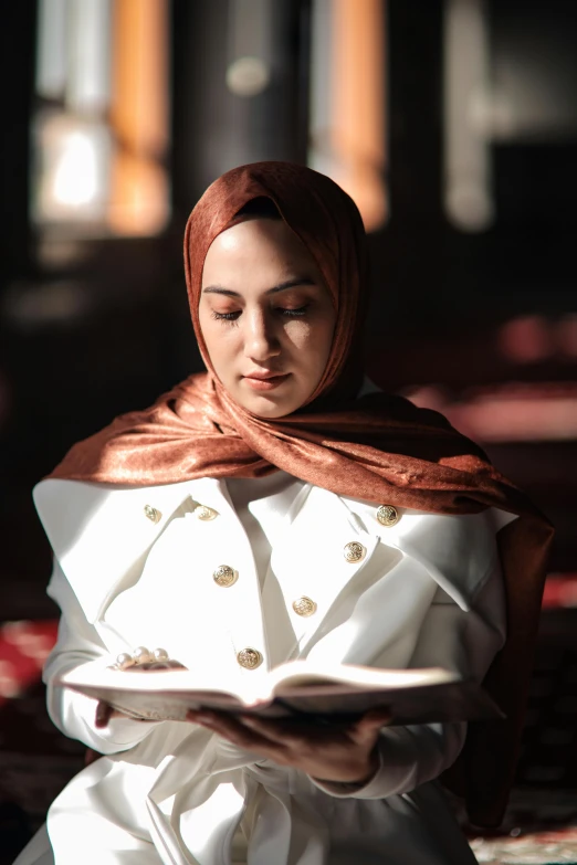 a young woman wearing a white suit and holding a book