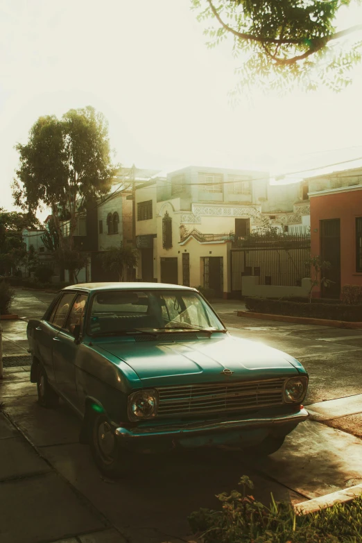 a small, old station wagon parked on the sidewalk near a row of houses