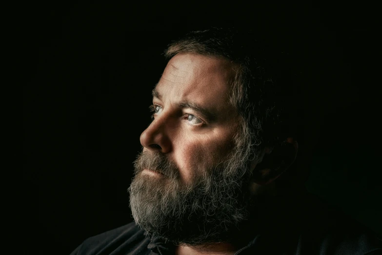 an older man with beard and dark background