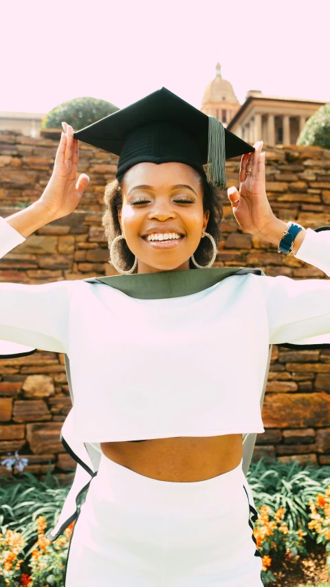an african american woman wearing a white graduation outfit