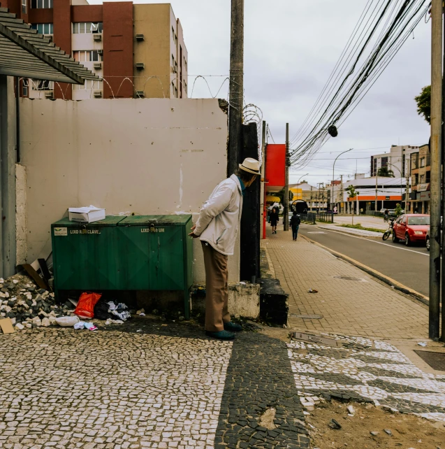 a person leaning against a pole on the side of a street