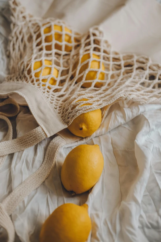 four lemons and a sack sitting on a bed