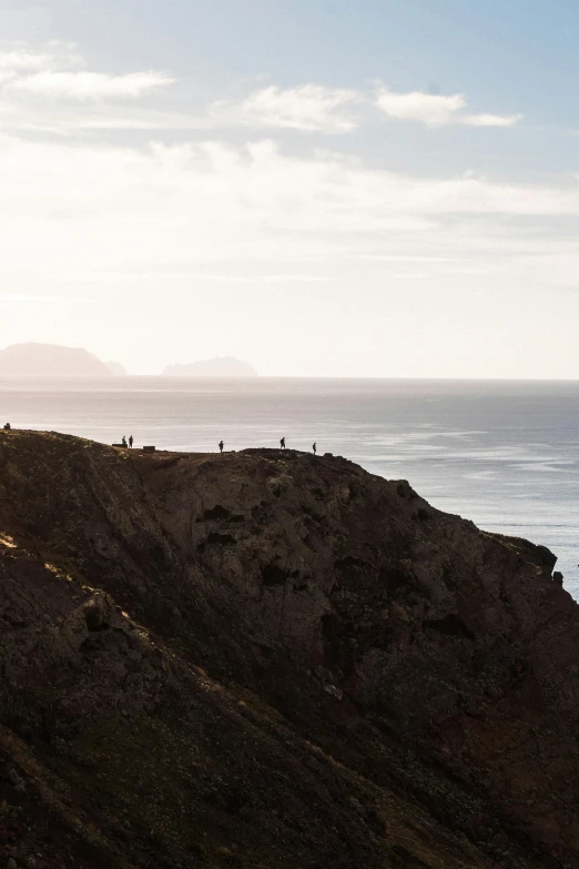 many people walking up to a cliff looking at the ocean