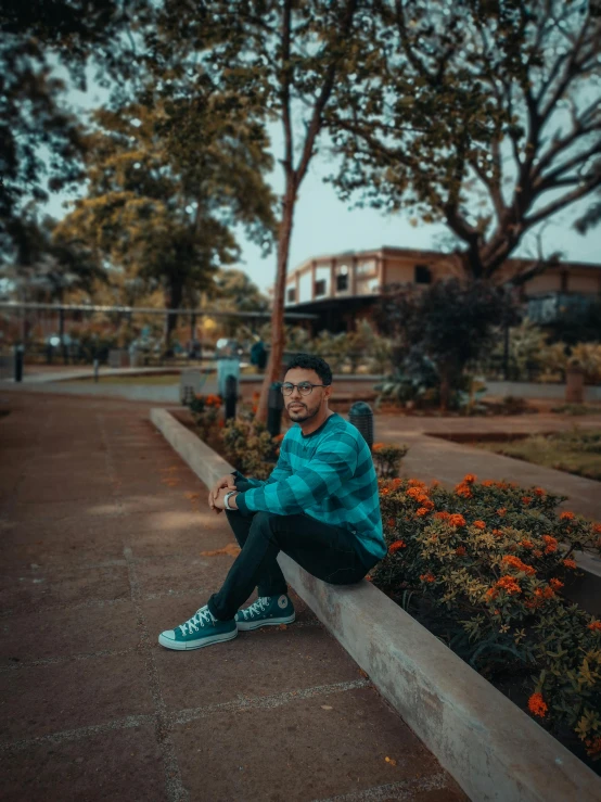 a man sitting on the side of a cement block next to some plants