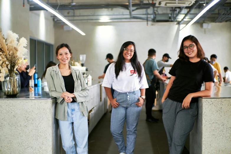 three young ladies standing near some tables in an office