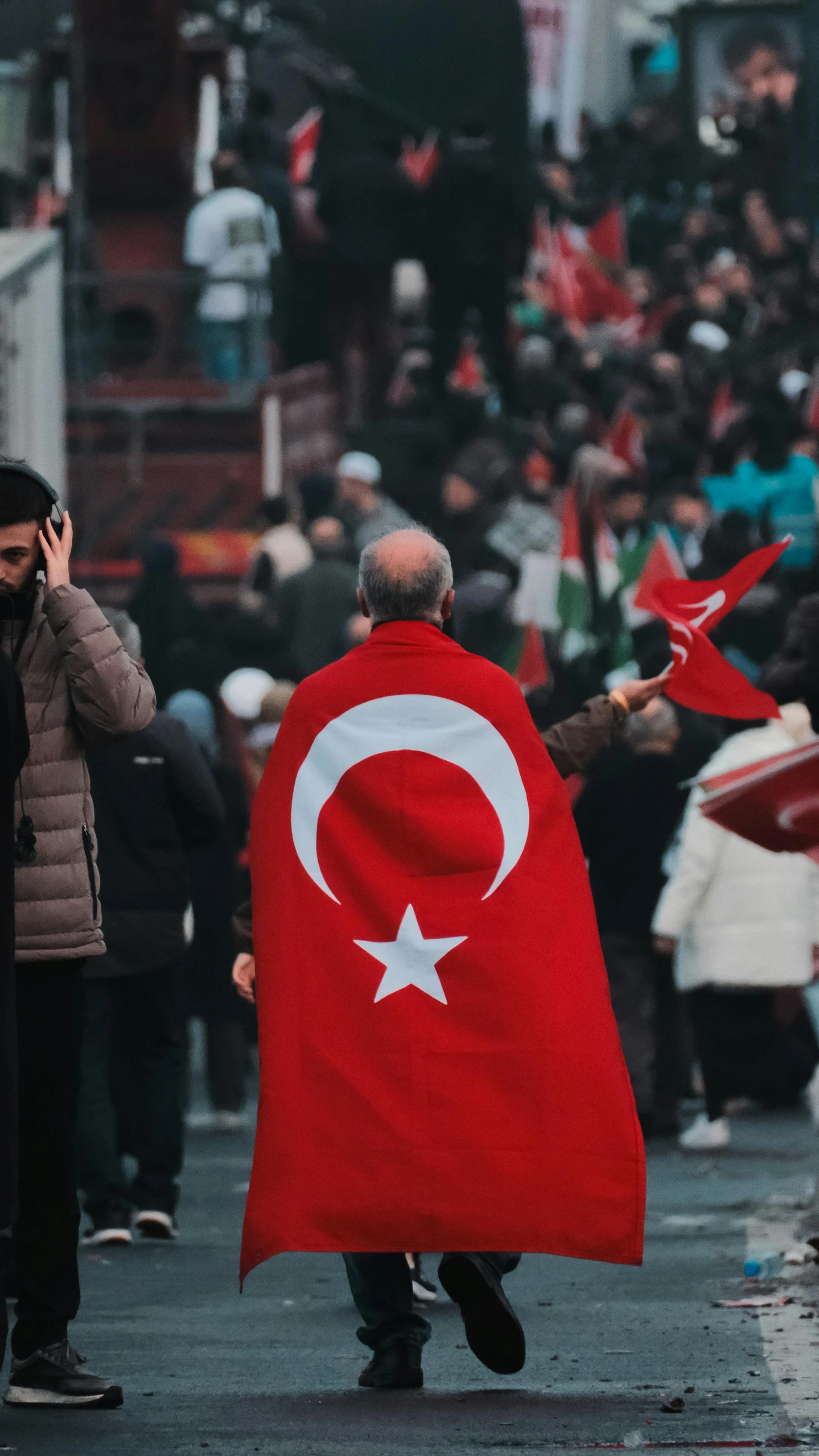 a man carrying a turkish flag talking on a cell phone