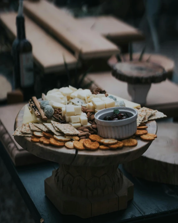 a wooden platter with cheeses, ers and berries on it