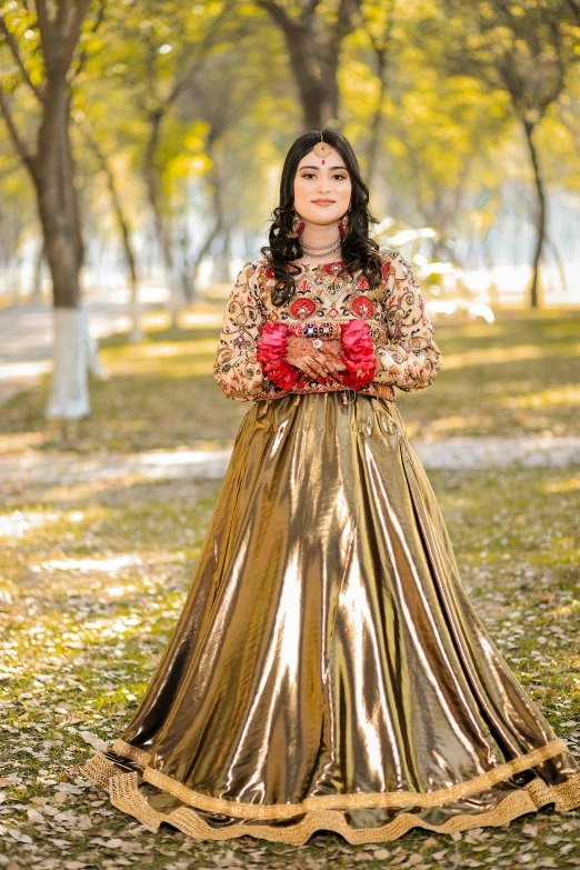 a young woman in an elegant, gold dress is shown in the park