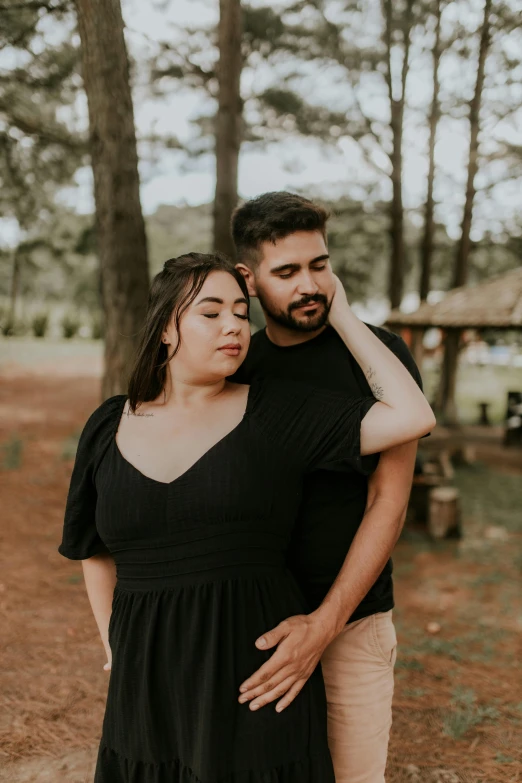 a woman is hugging a man in the woods