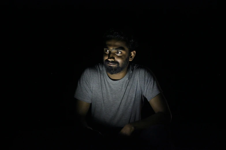 a bearded man in the dark posing for a picture