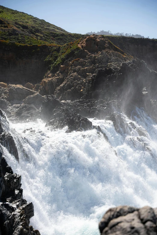 a waterfall surrounded by a rocky mountain is coming out of the water