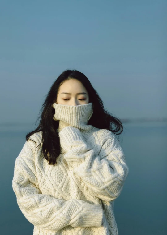 a young woman with her eyes closed and wearing a sweater