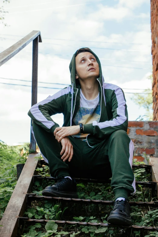 young man sitting down in the grass on some stairs