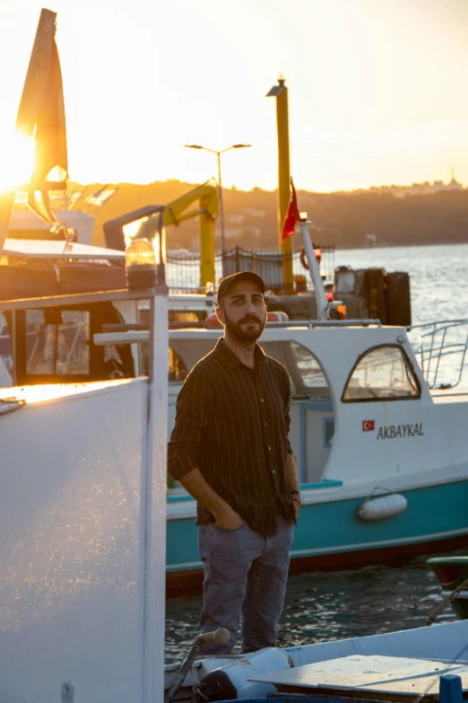 a man in a hat standing on the dock by the water