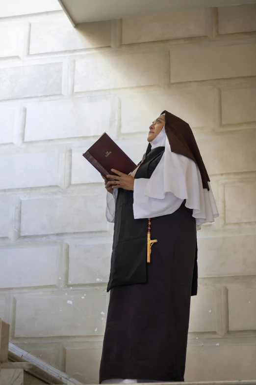 man in priest's robes, holding a bible and looking off into the distance