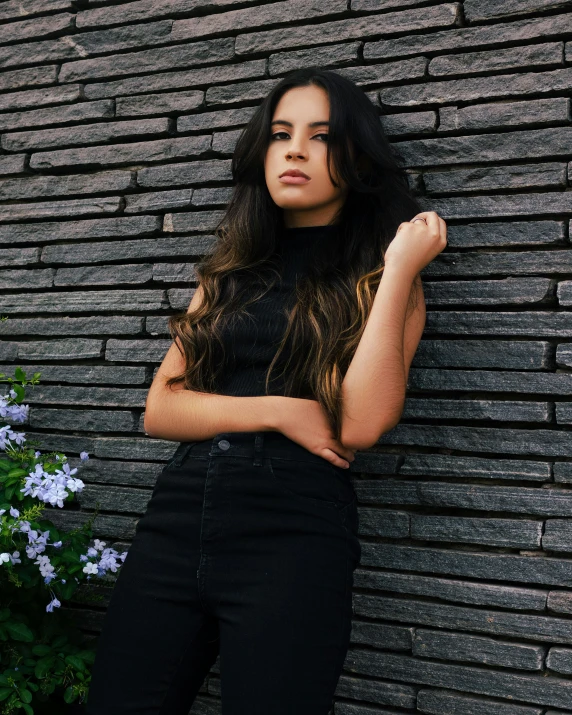 a woman is leaning against a brick wall