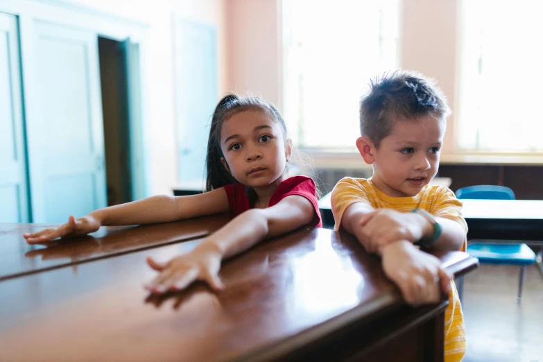 two children are in a room sitting at a desk