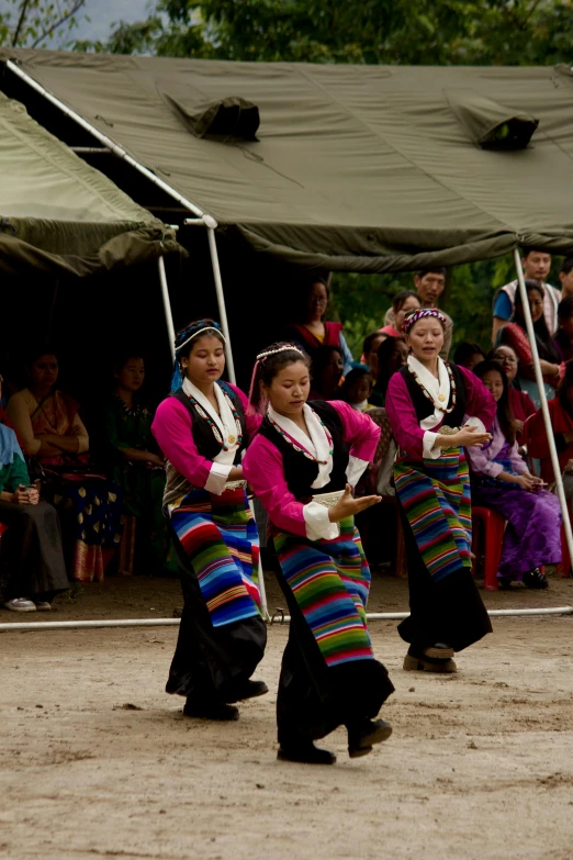 women dressed in ethnic style dancing together under tent