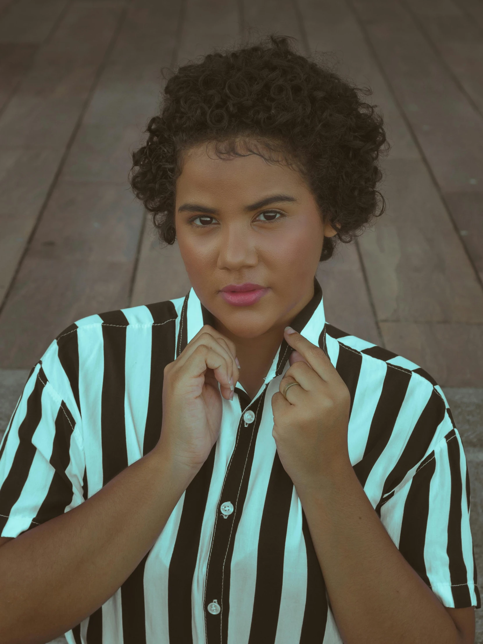 a woman is posing on the steps in a striped shirt